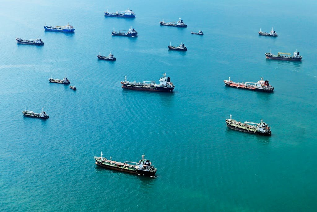 Numerous cargo ships anchored on the blue ocean, captured from above.